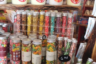 Photo of a colorful assortment of candies and sweets neatly displayed on wooden shelves.