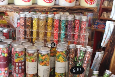 A vibrant display of assorted candies in transparent jars with green labels.