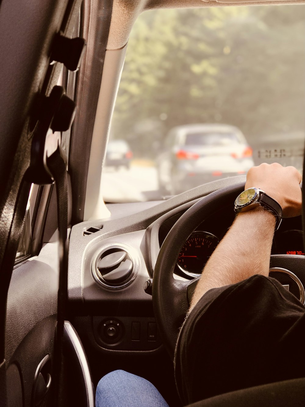 Persona con camisa de manga larga negra conduciendo un automóvil durante el día