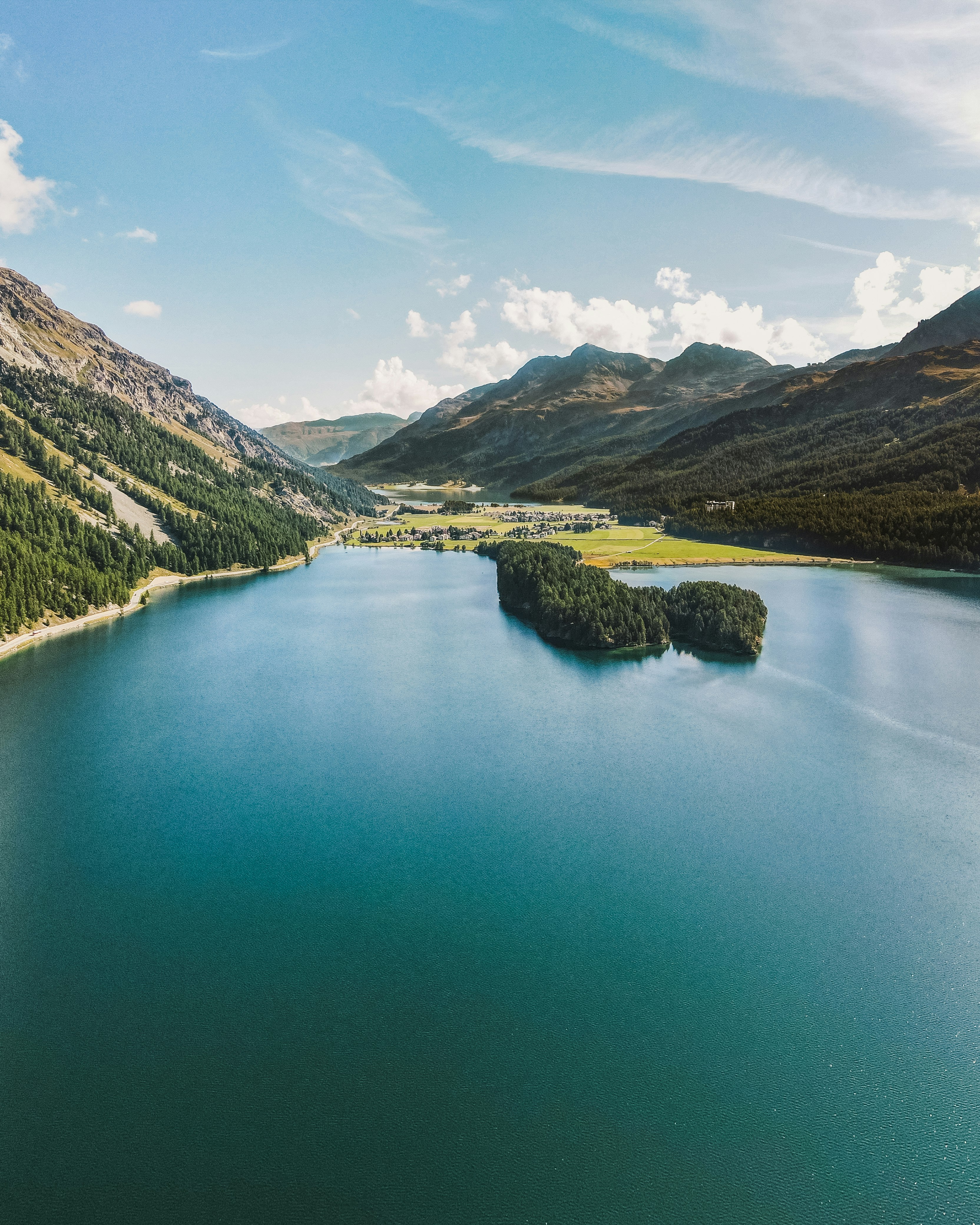 green lake surrounded by green mountains during daytime