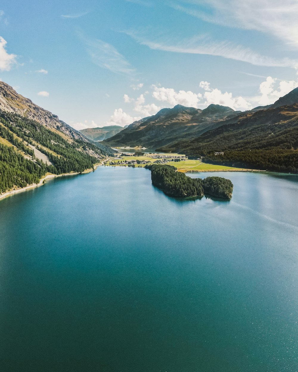 green lake surrounded by green mountains during daytime