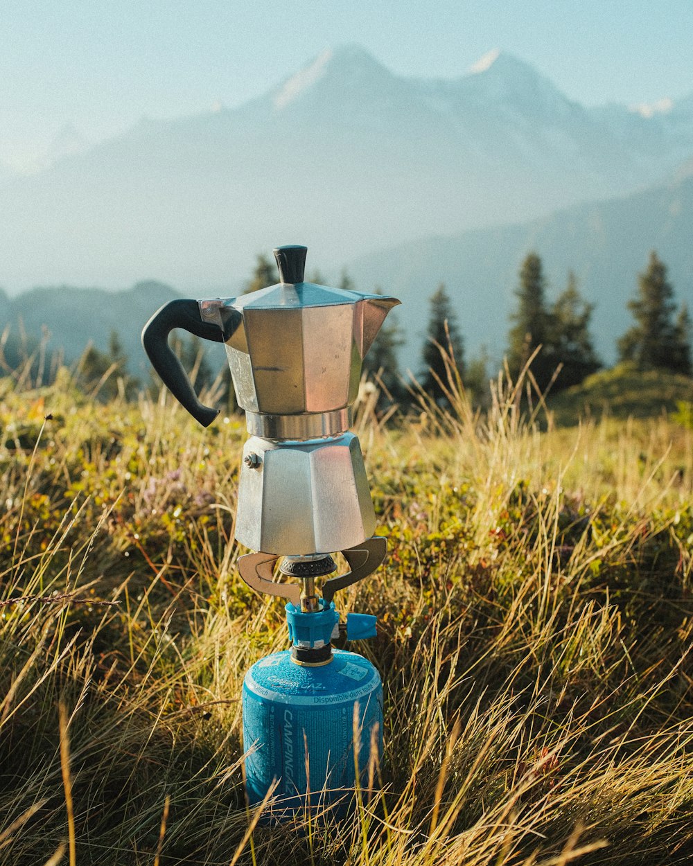 blue and silver coffee pot on green grass field during daytime