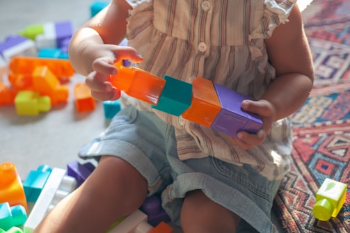 A cheerful child playing with colorful building blocks in a bright classroom.