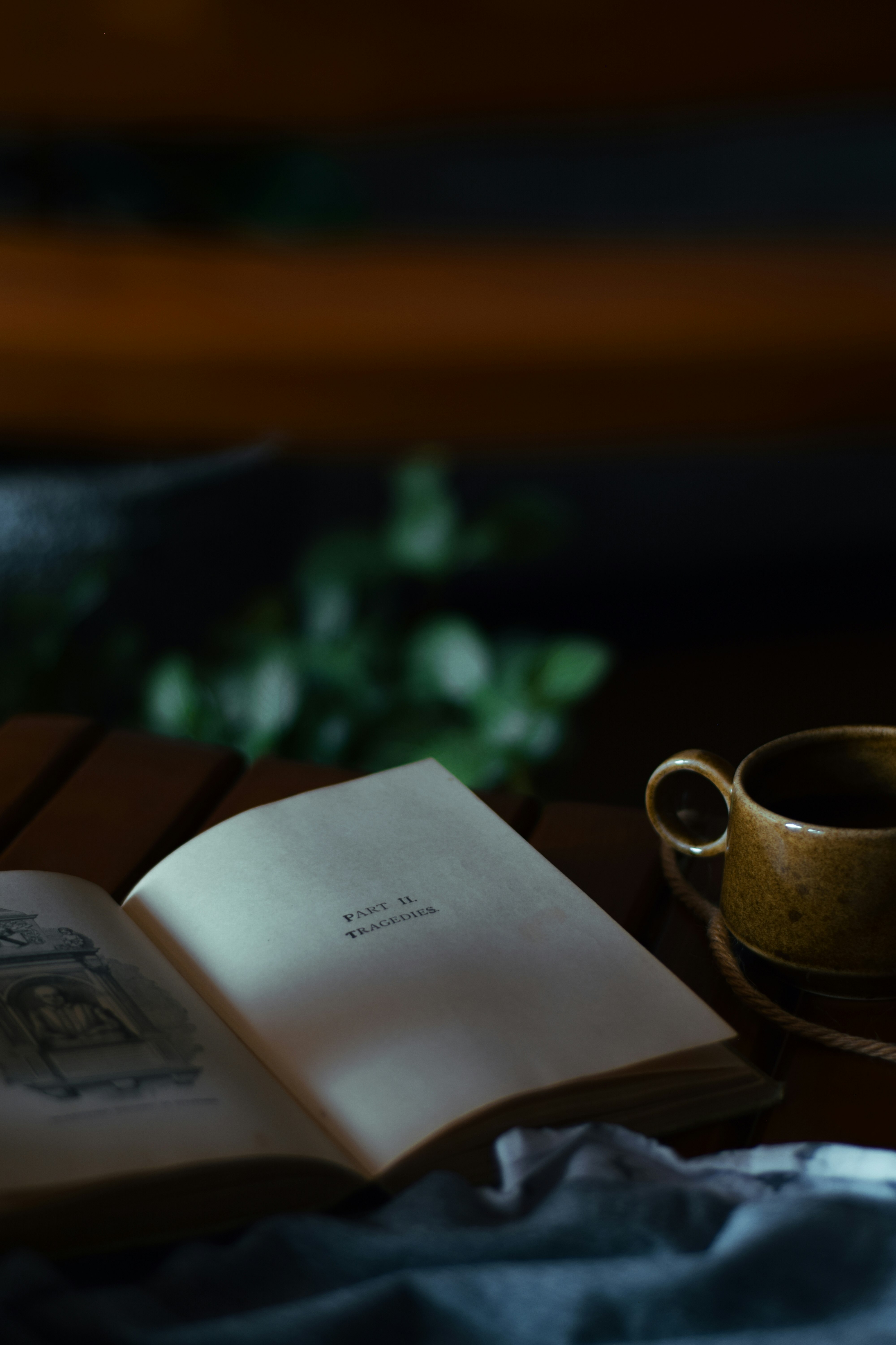 white book beside brown ceramic mug on brown wooden table