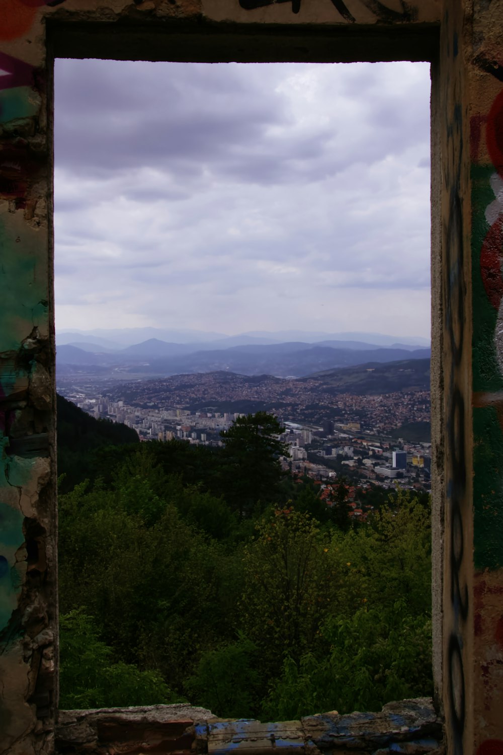 green trees and mountains under cloudy sky during daytime