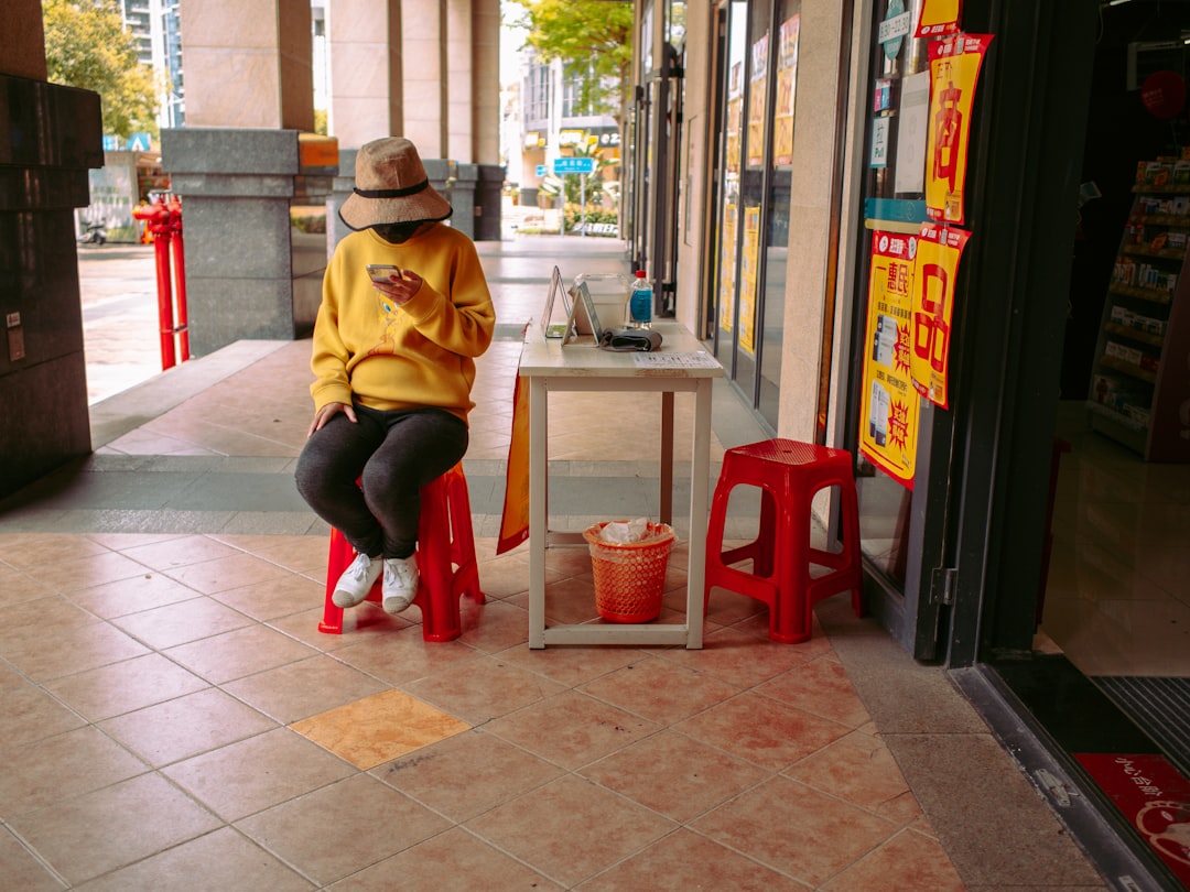 woman in yellow hoodie sitting on red plastic seat