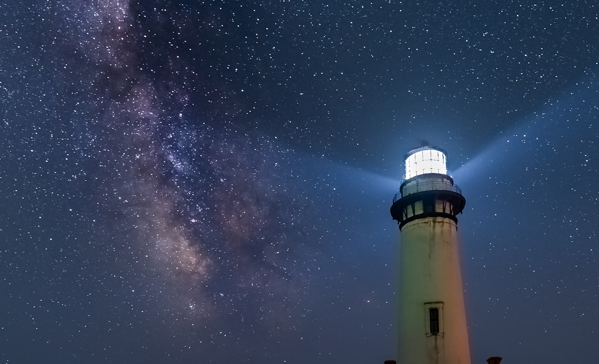 white and black light house under starry night