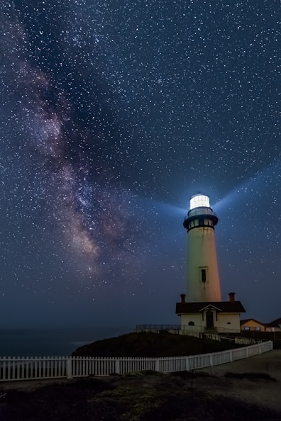 white and black light house under starry night