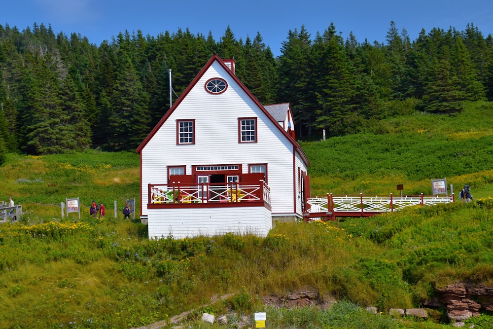 casa de madeira branca e vermelha no campo verde da grama