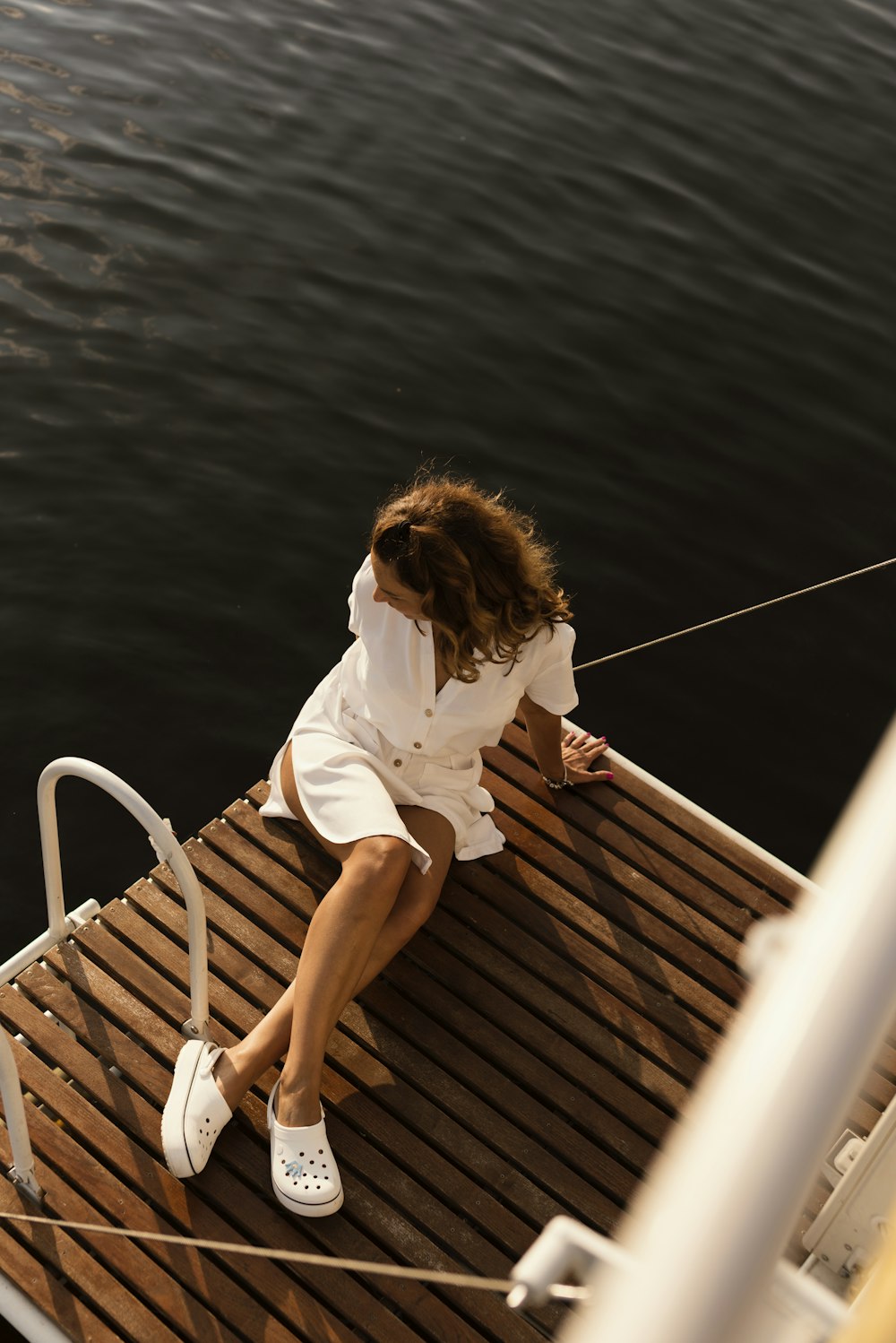 woman in white shirt and brown skirt sitting on white metal railings