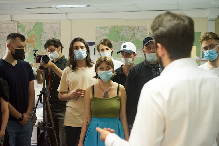 mujer con camiseta verde junto a hombres en epoca de pandemia y con barbijos