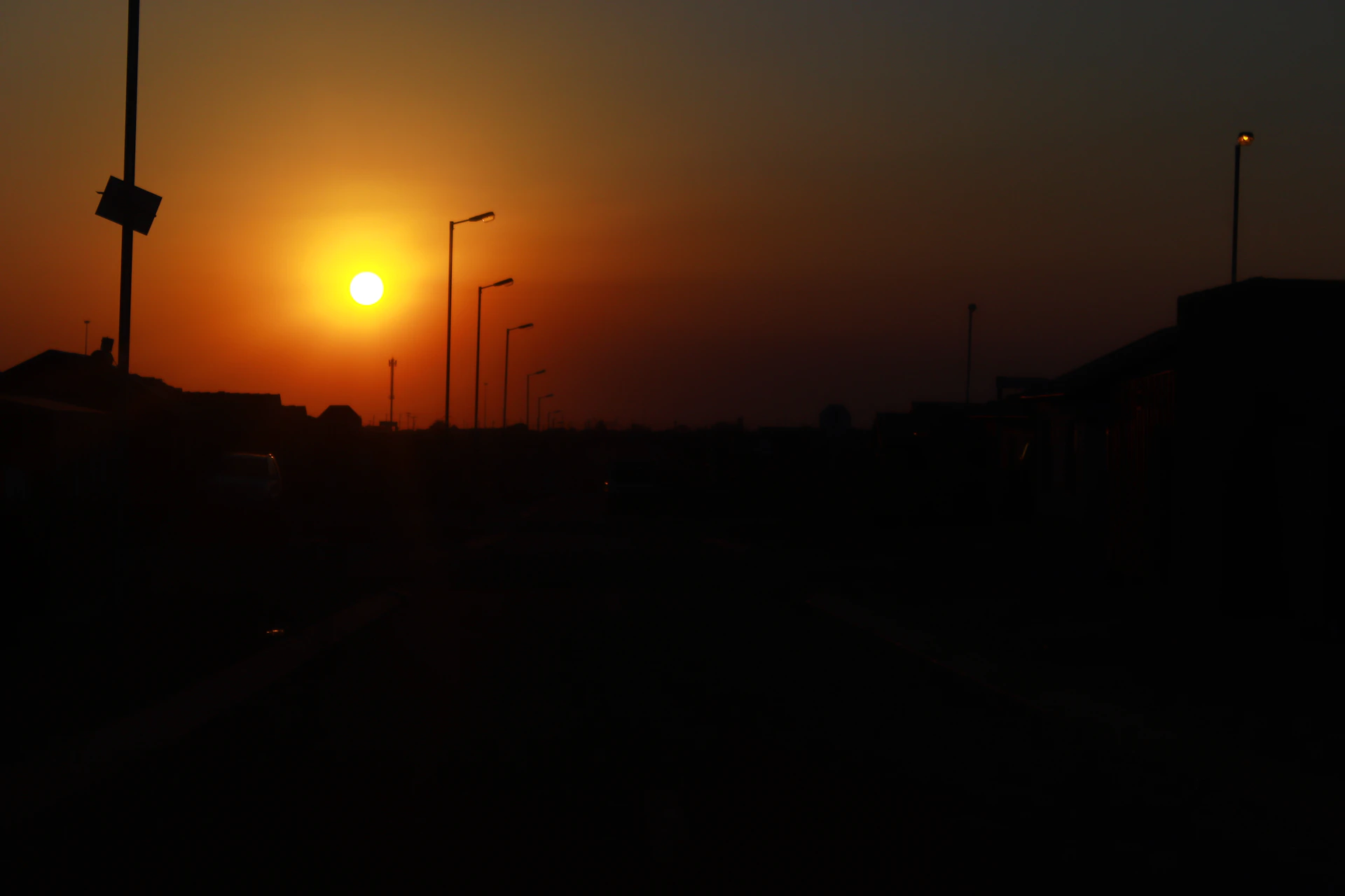A warm, candid photo of a golden hour sunset casting soft light over a quiet street, capturing the peaceful vibe of everyday moments.