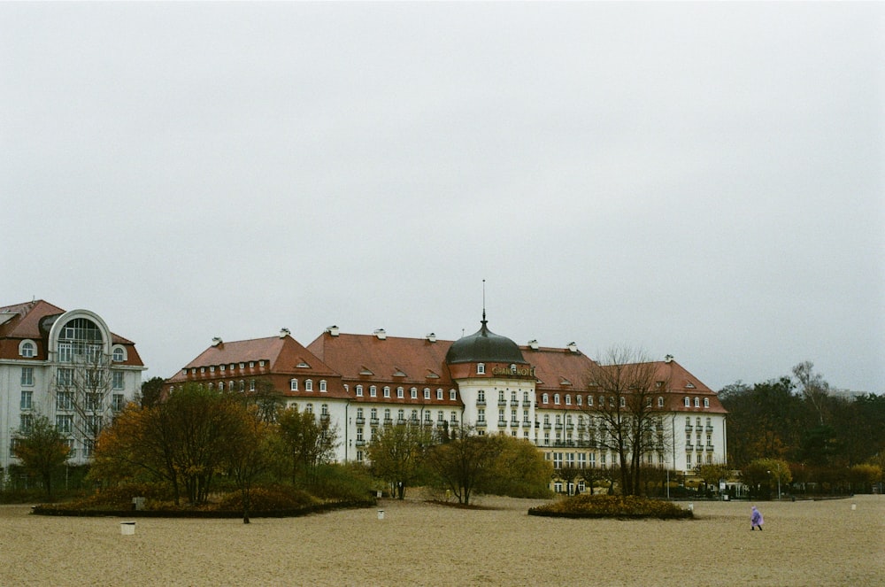 white and brown concrete building near green trees under white sky during daytime