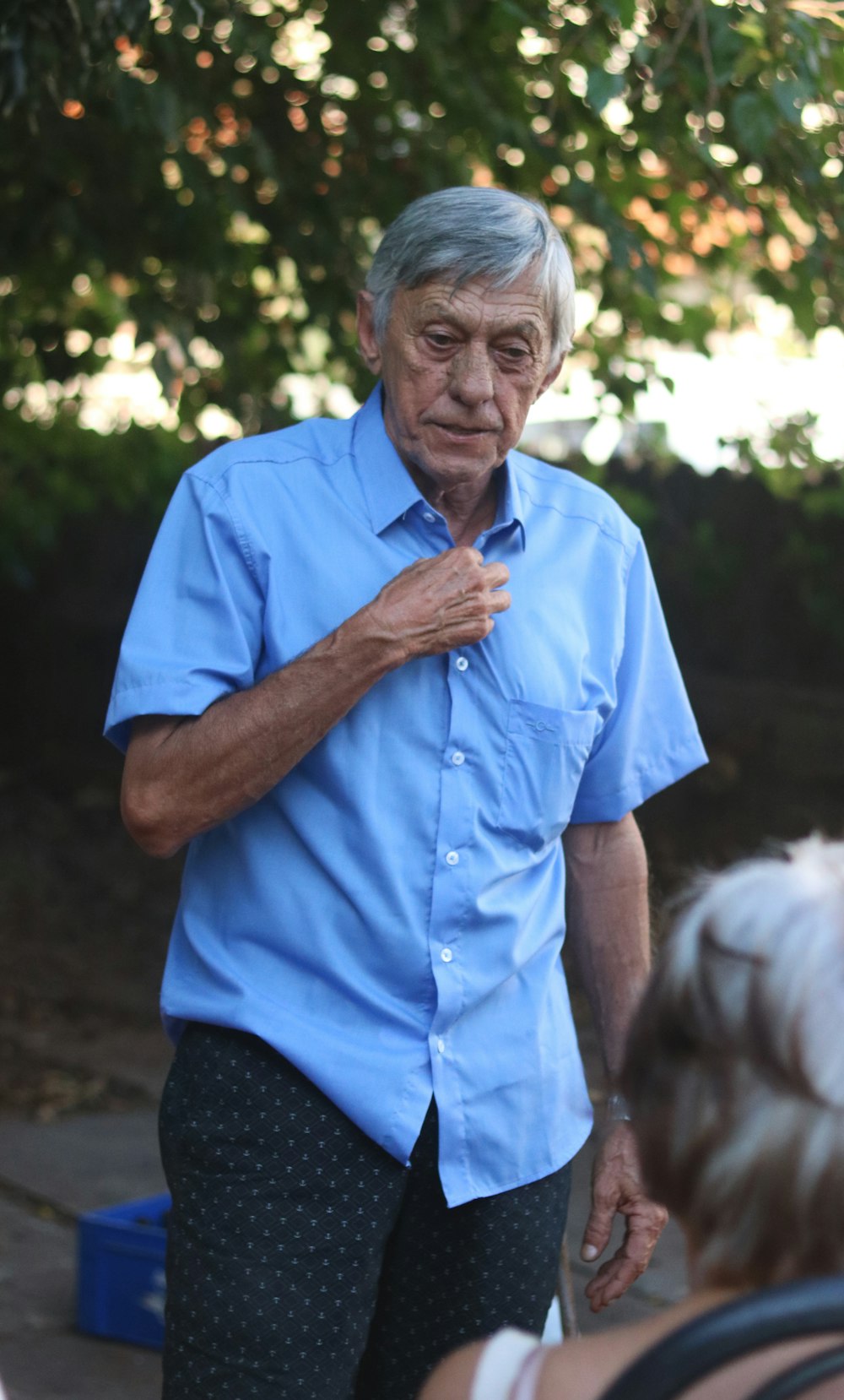 man in blue button up shirt standing near green trees during daytime