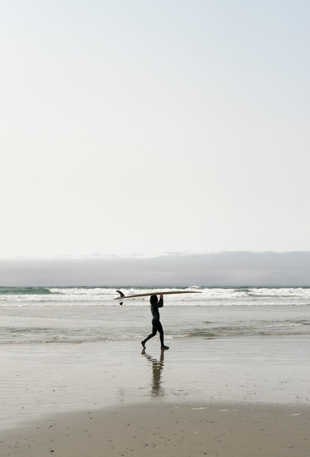 person holding surfboard walking on beach during daytime