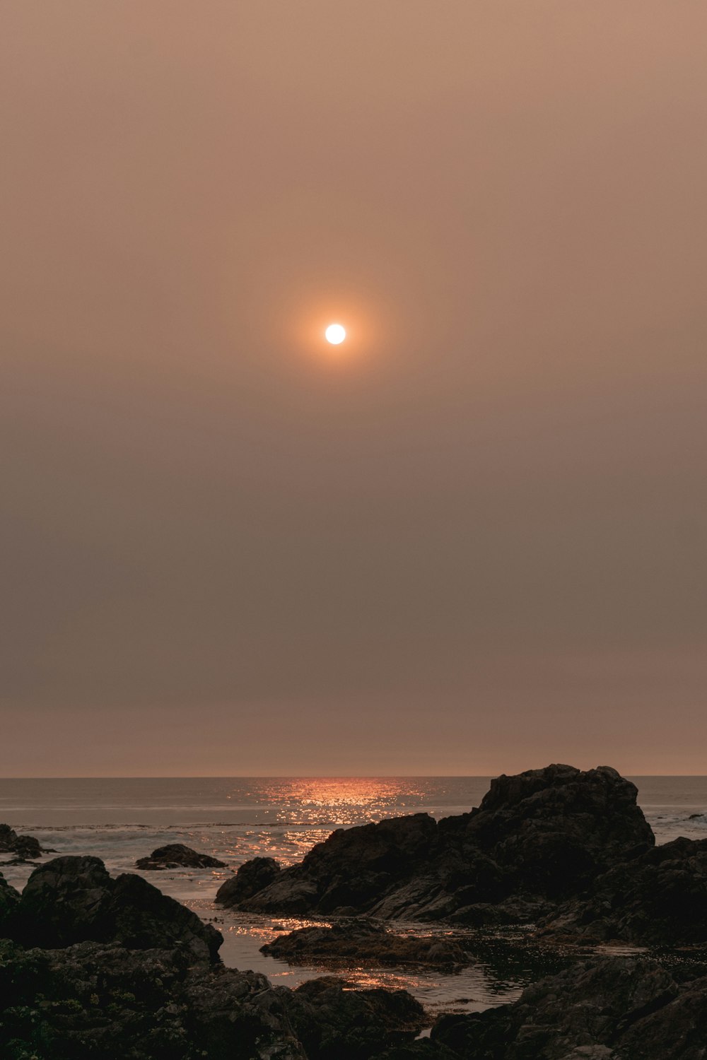 silhouette of rock formation on sea shore during sunset