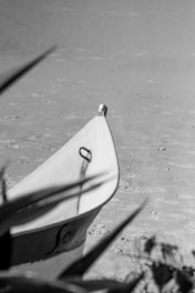 Black and white cinematic photo of a ship's bow cutting through calm ocean waters at dawn.