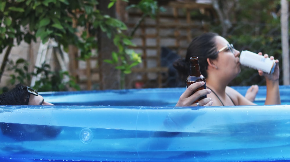 mulher na piscina azul segurando a câmera preta do dslr