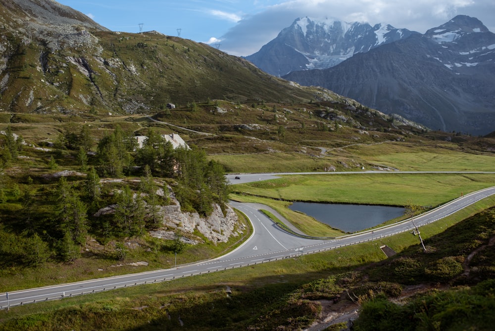 green grass field and gray concrete road