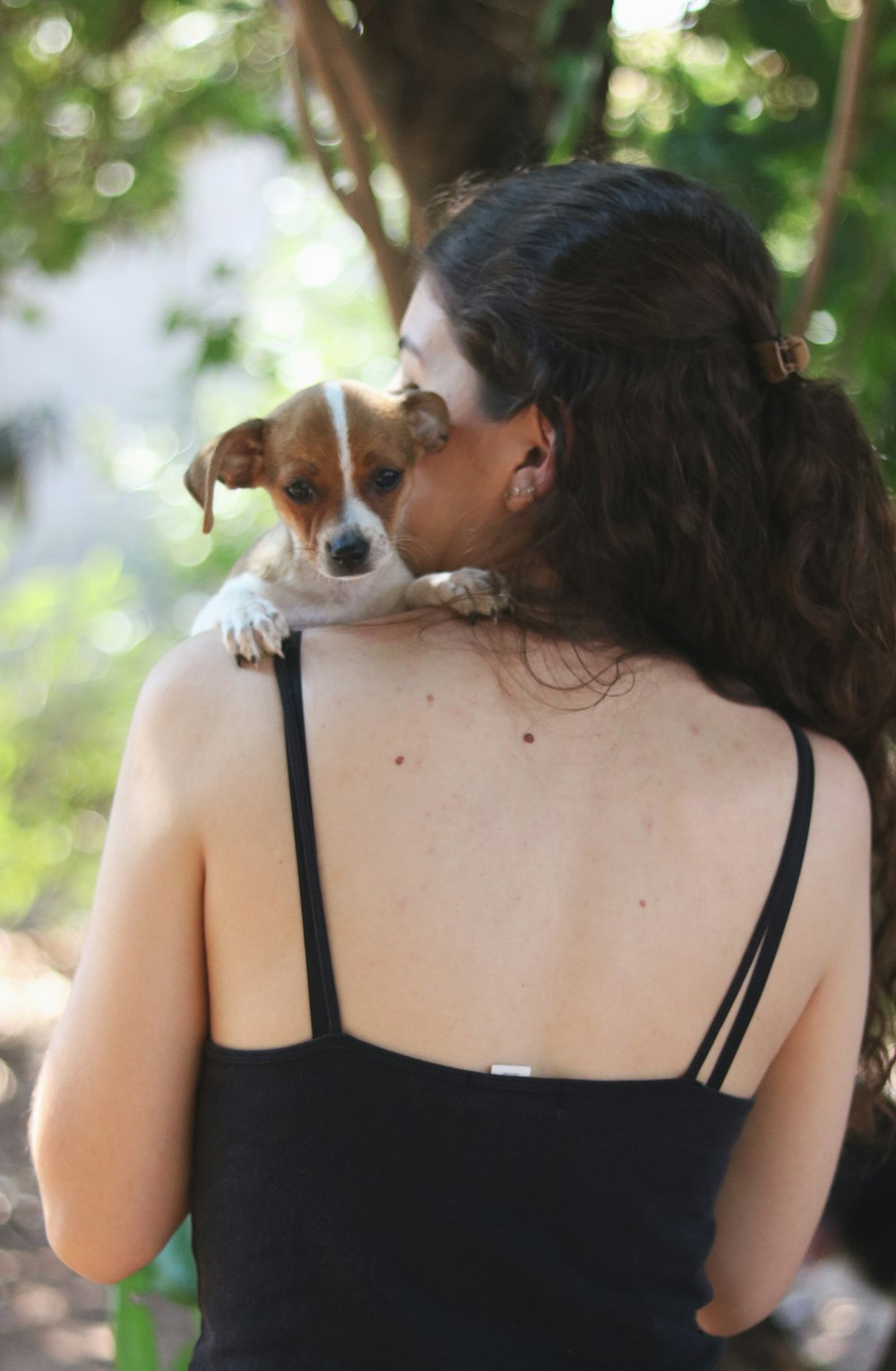 woman in black tank top carrying brown and white short coated dog