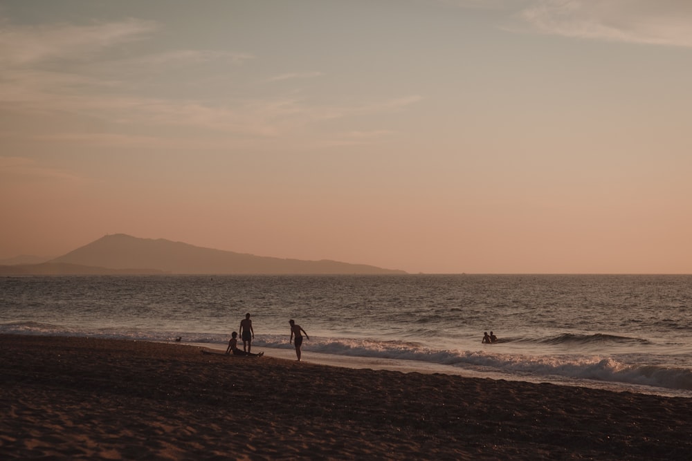 pessoas andando na praia durante o pôr do sol