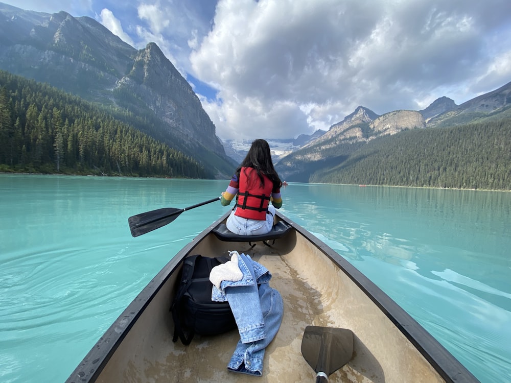 woman in red and black jacket sitting on boat during daytime