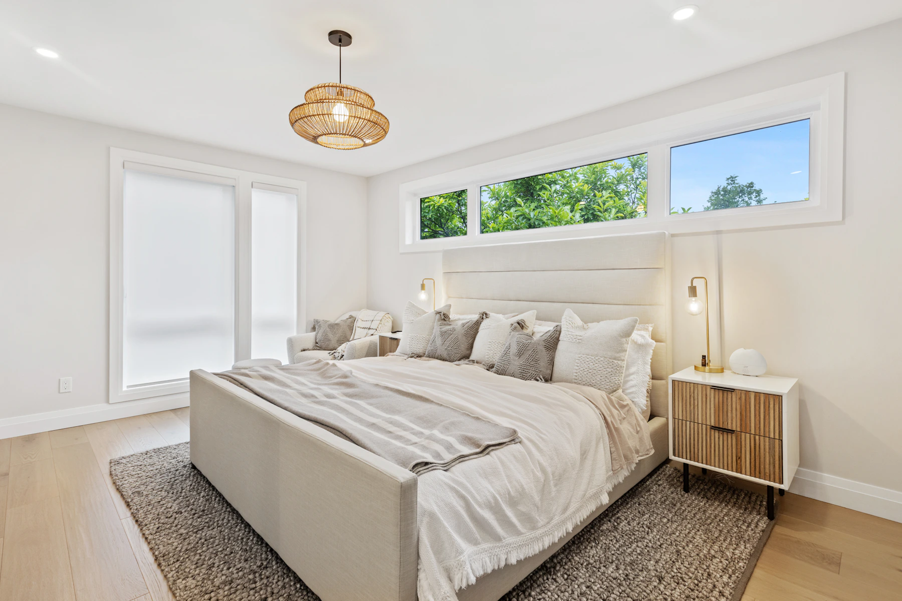 Cream upholstered bed with a soft grey area rug over a light wood floor
