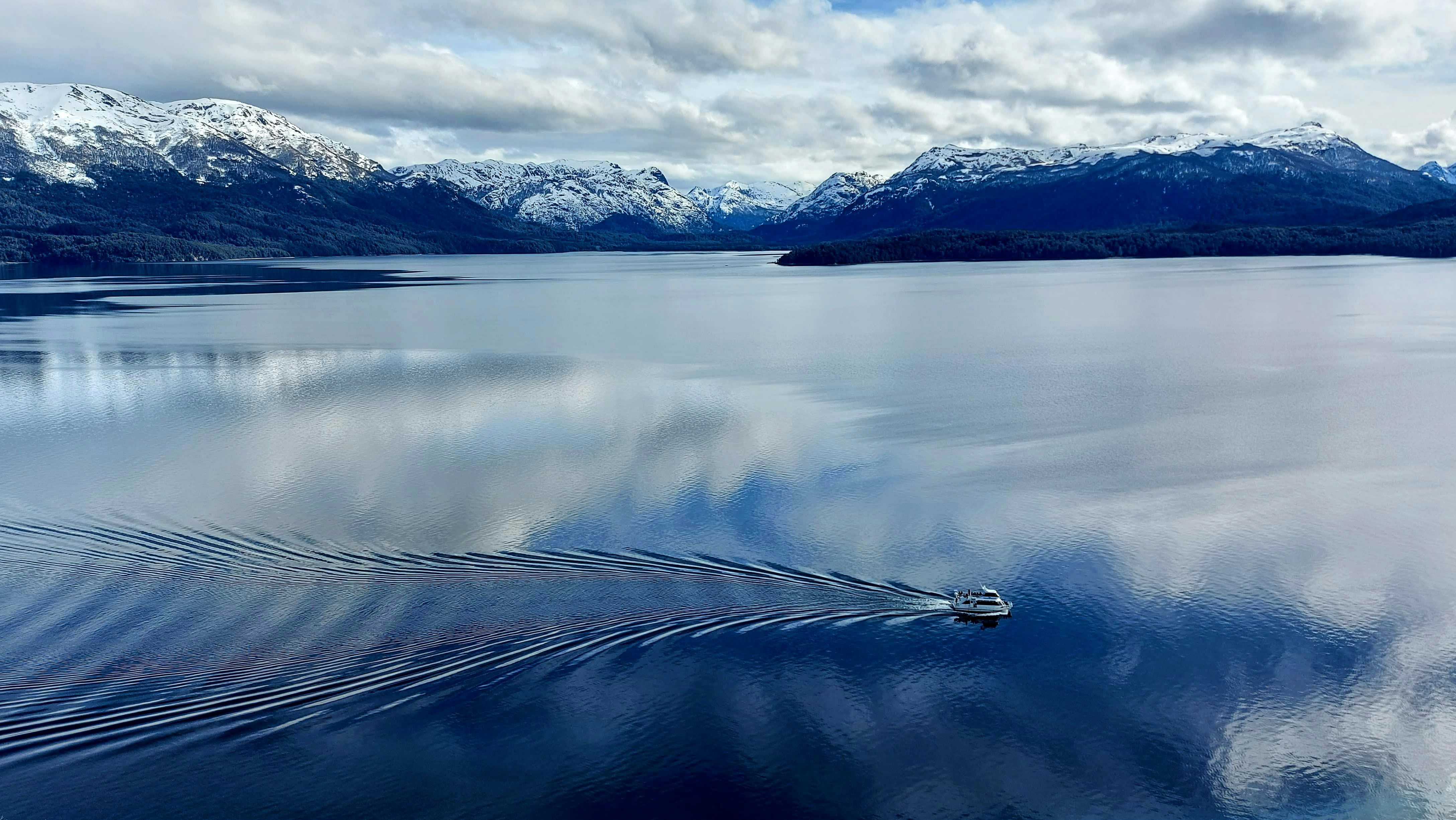 body of water near mountain under white clouds during daytime