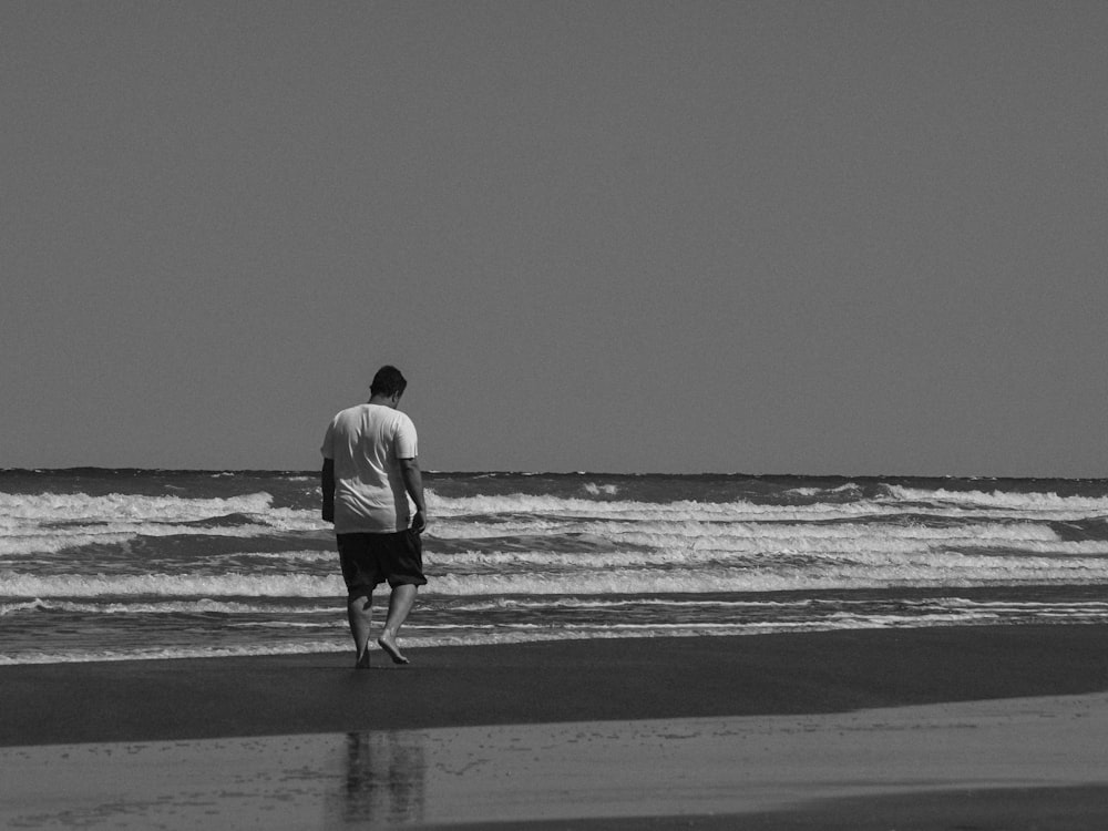 man in white shirt walking on beach
