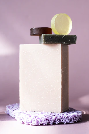 A softly lit arrangement of artisan soaps with celestial moon and star motifs resting on a lilac gradient background.