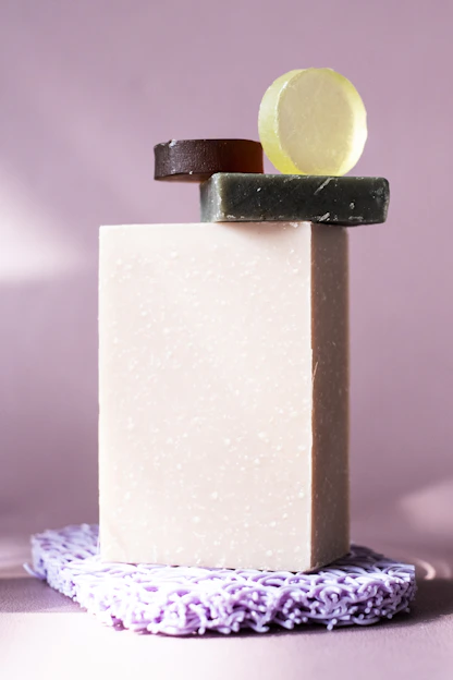 A softly lit arrangement of artisan soaps with celestial moon and star motifs resting on a lilac gradient background.