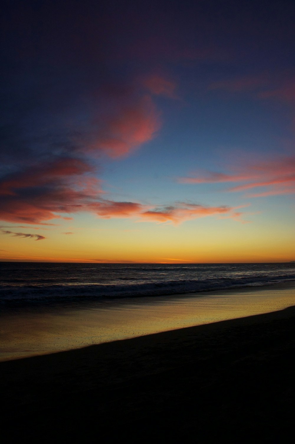 Specchio d'acqua sotto il cielo arancione e blu durante il tramonto