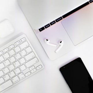 A close-up of a sleek laptop with accessories like headphones and cables neatly arranged around it.