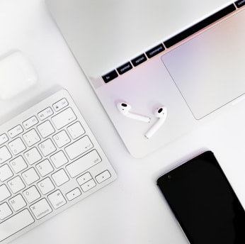 A close-up of a sleek laptop with accessories like headphones and cables neatly arranged around it.