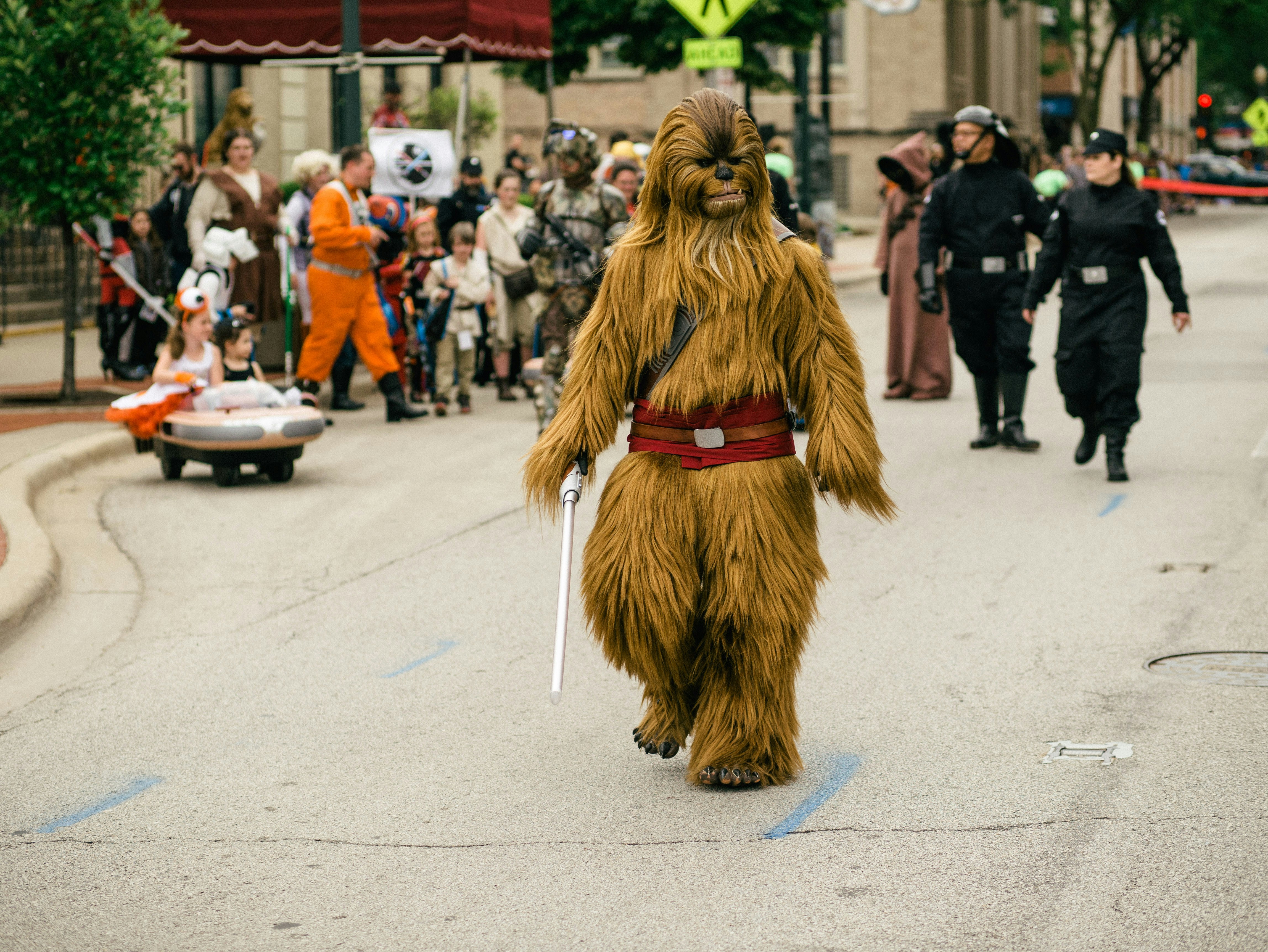 mulher no vestido marrom de manga comprida andando na estrada cinza do asfalto durante o dia