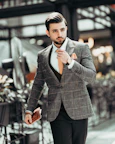 man in black suit jacket holding his necktie