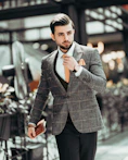 man in black suit jacket holding his necktie