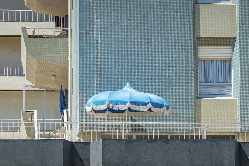 blue and white umbrella on gray concrete wall