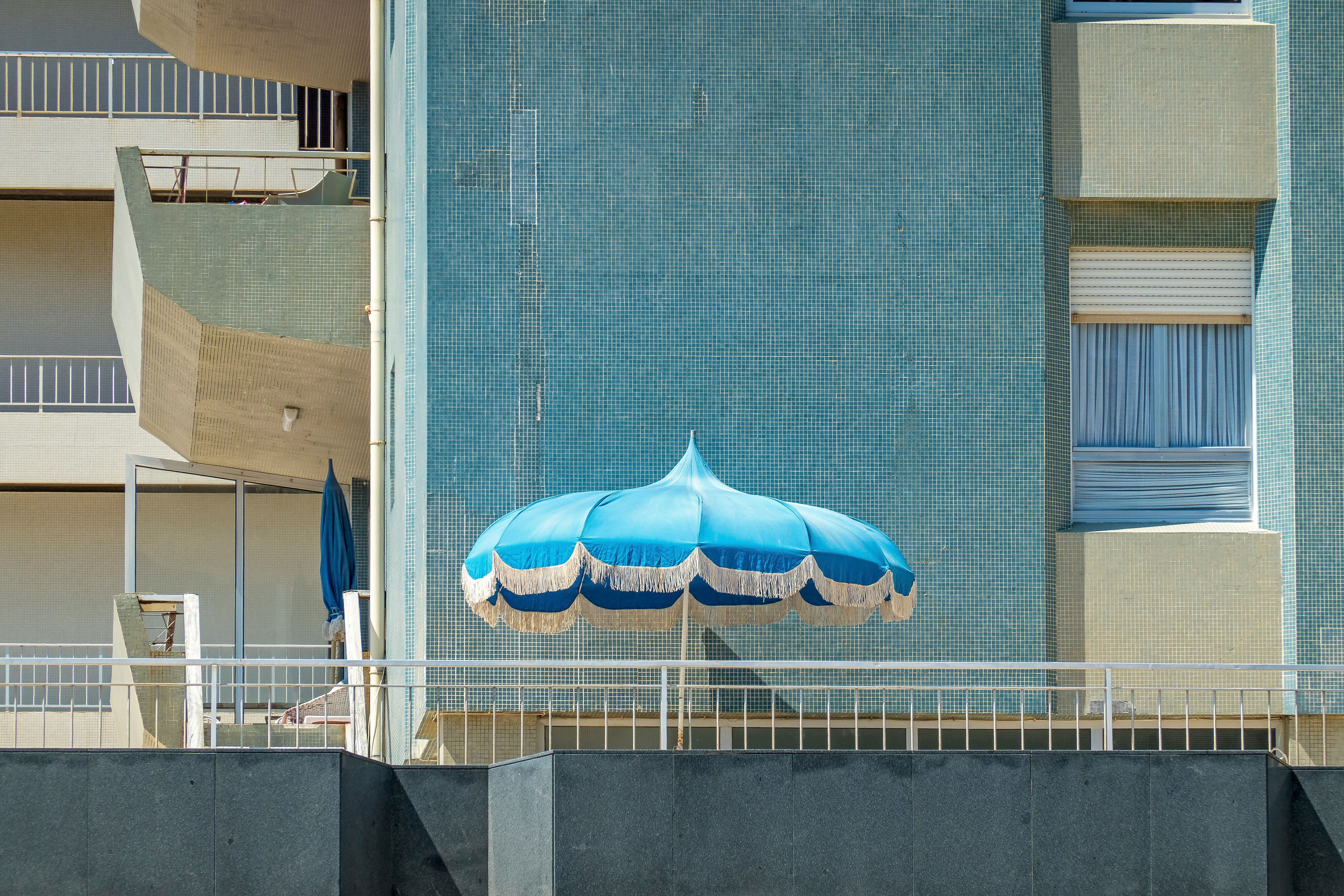 blue and white umbrella on gray concrete wall