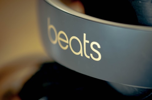 A close-up view of a pair of headphones featuring the brand name 'beats' prominently displayed on the side in light-colored text. The background is blurred, highlighting the focus on the branding.