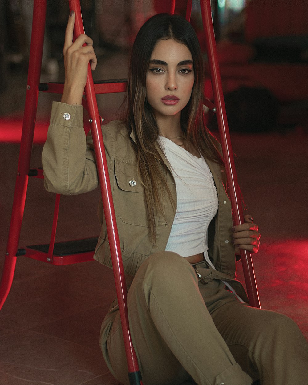 Femme en chemise blanche à manches longues assise sur une chaise en métal rouge