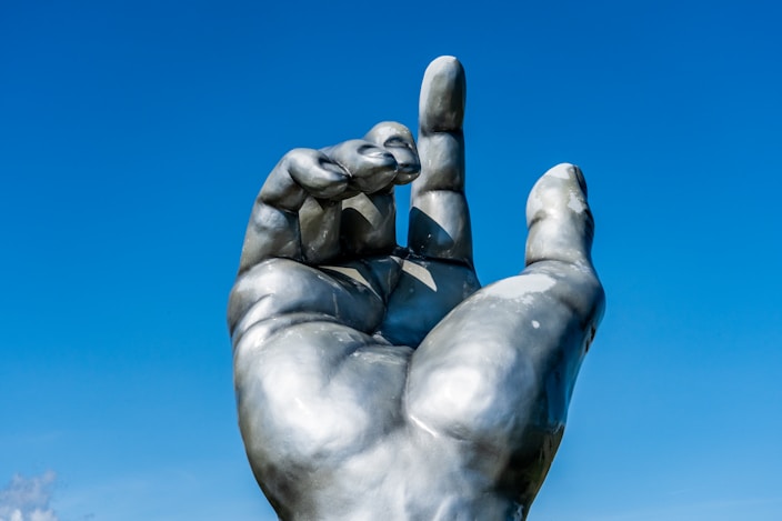 man in black jacket and blue denim jeans sitting on concrete statue