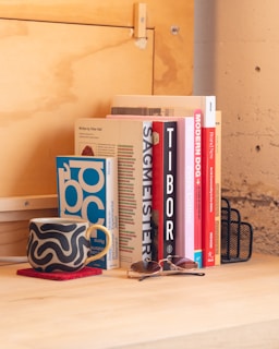 Bryan Wempen sitting at a rustic wooden desk in his Santa Fe home, surrounded by stacks of books and a steaming cup of coffee.