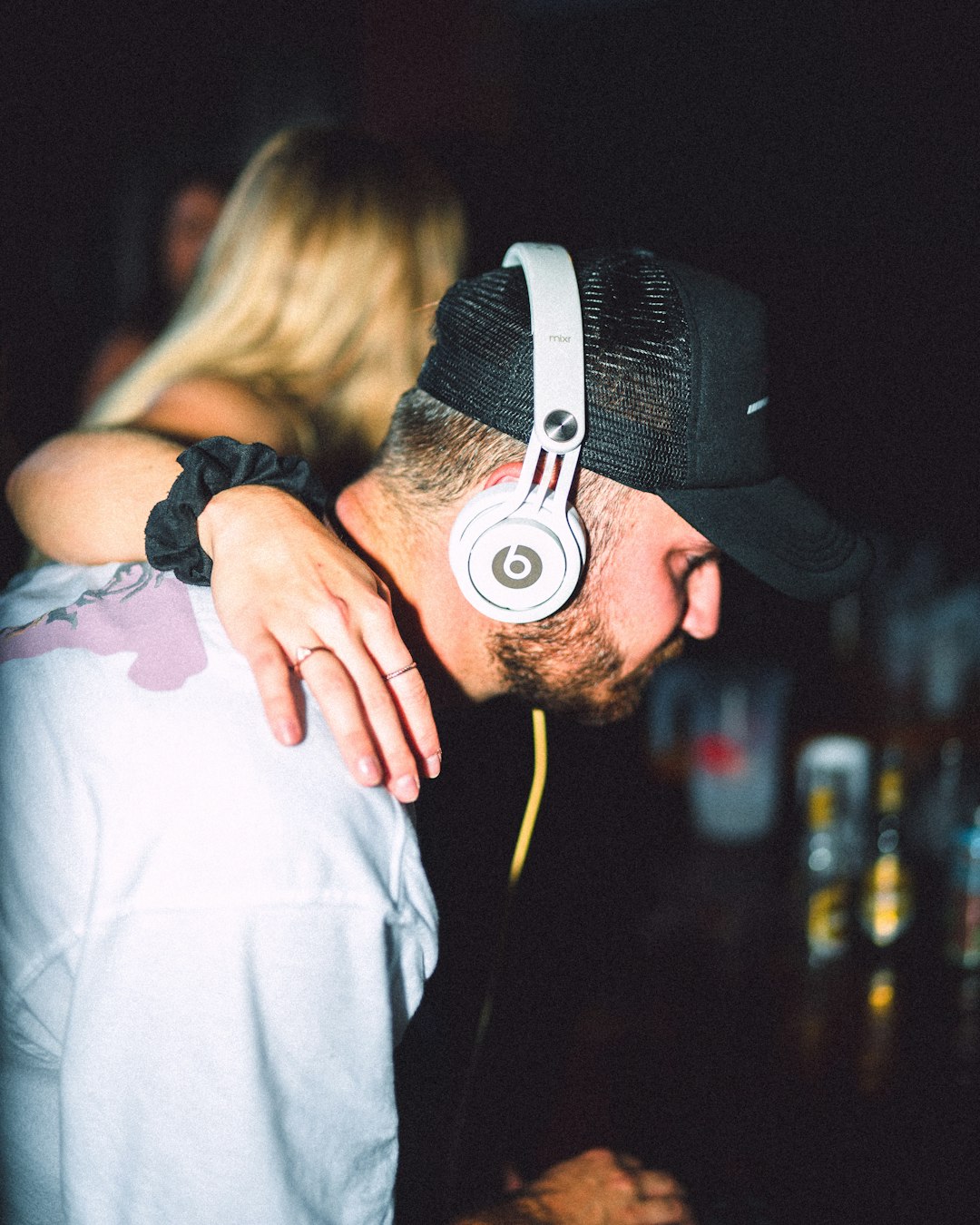 man in white shirt wearing black cap kissing womans cheek