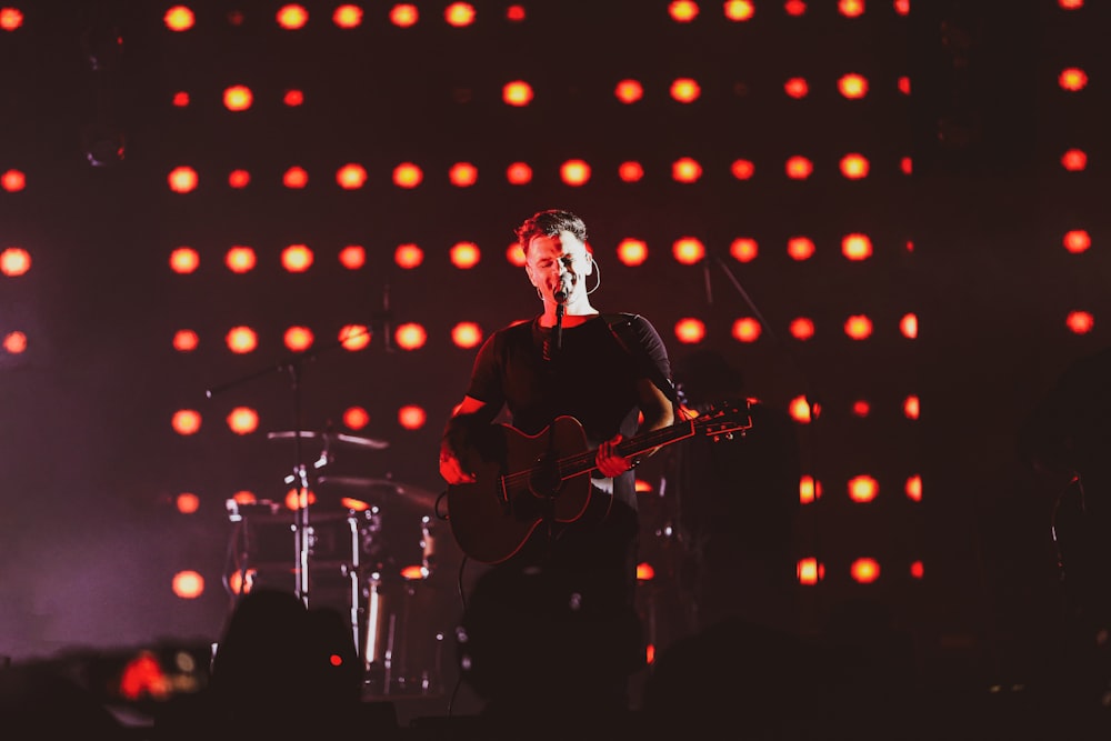 man in black shirt playing guitar on stage