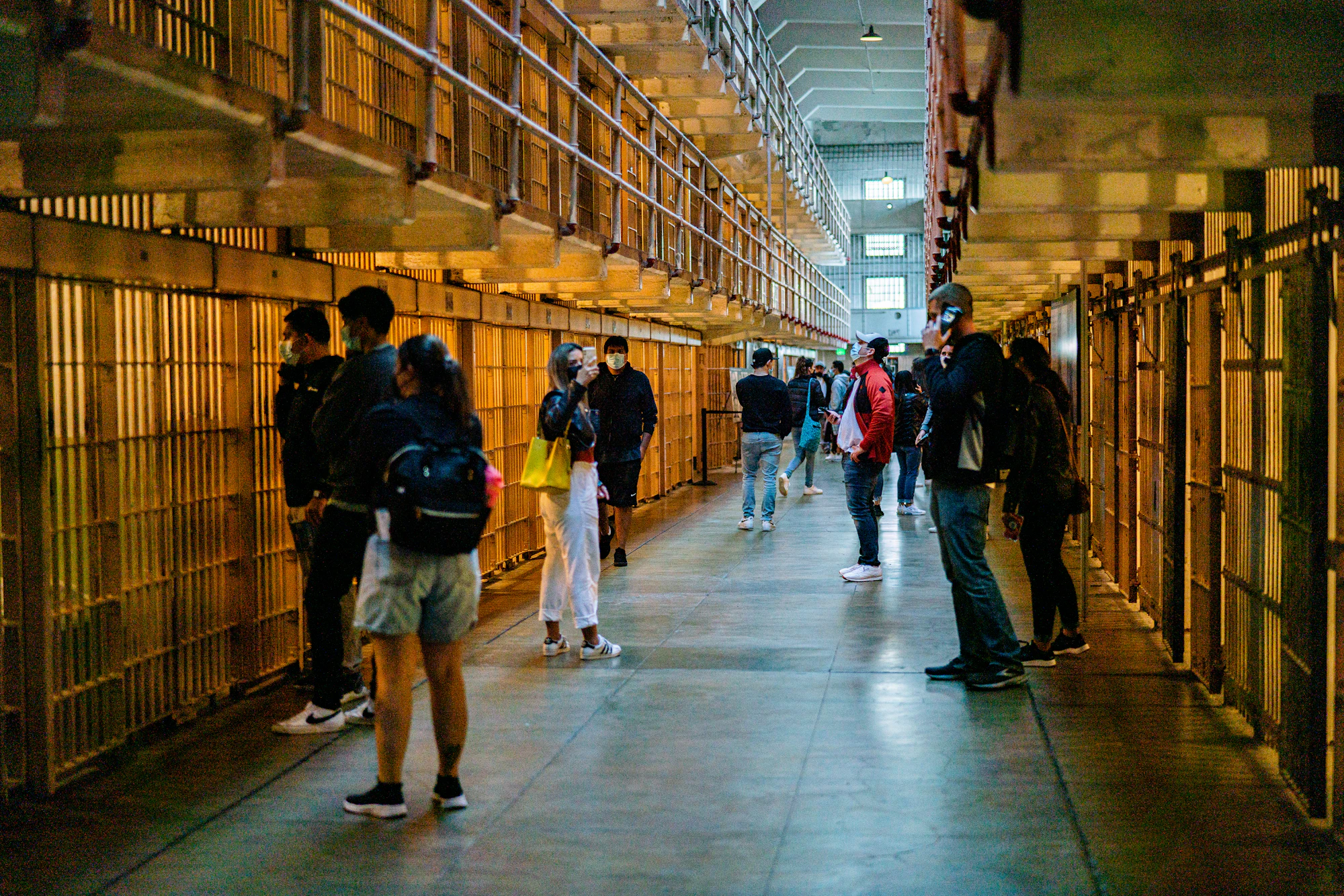 A lone figure walking down a long, dim prison cell hallway