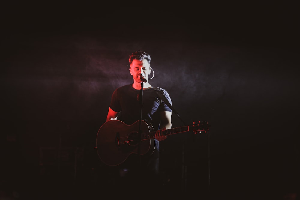 man in black shirt singing on stage