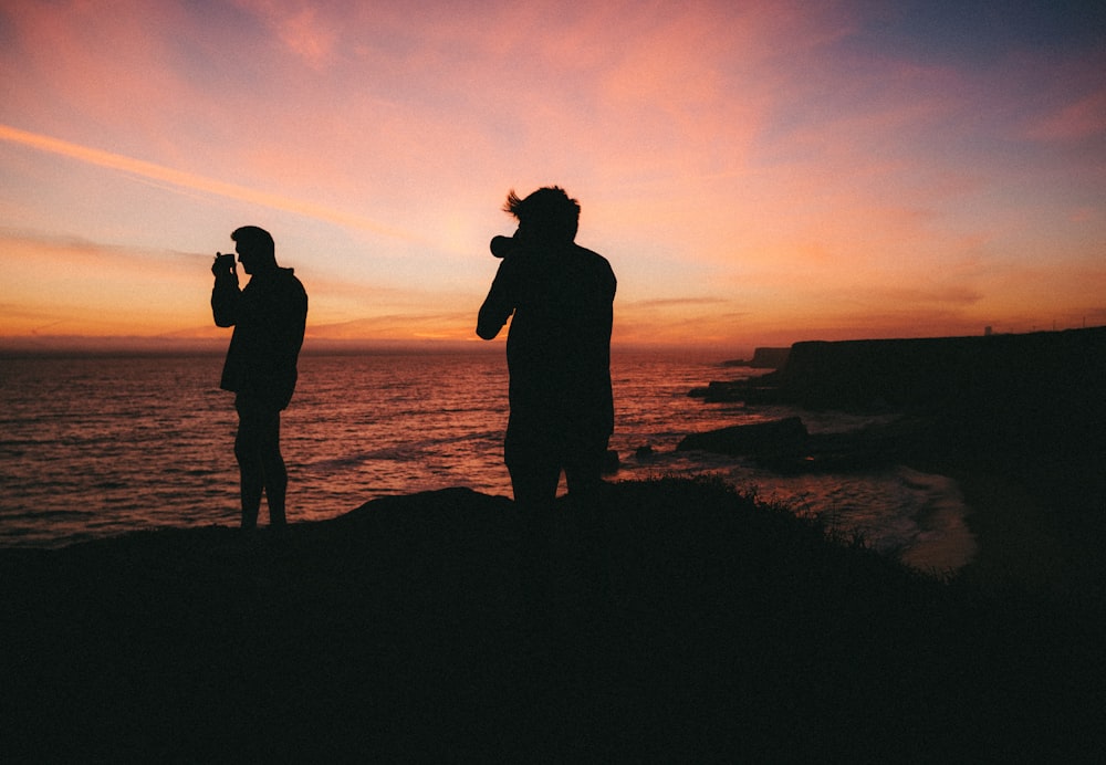 夕暮れ時のビーチでキスをするカップルのシルエット