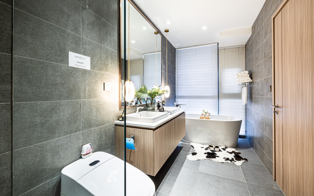 white ceramic bathtub beside brown wooden cabinet