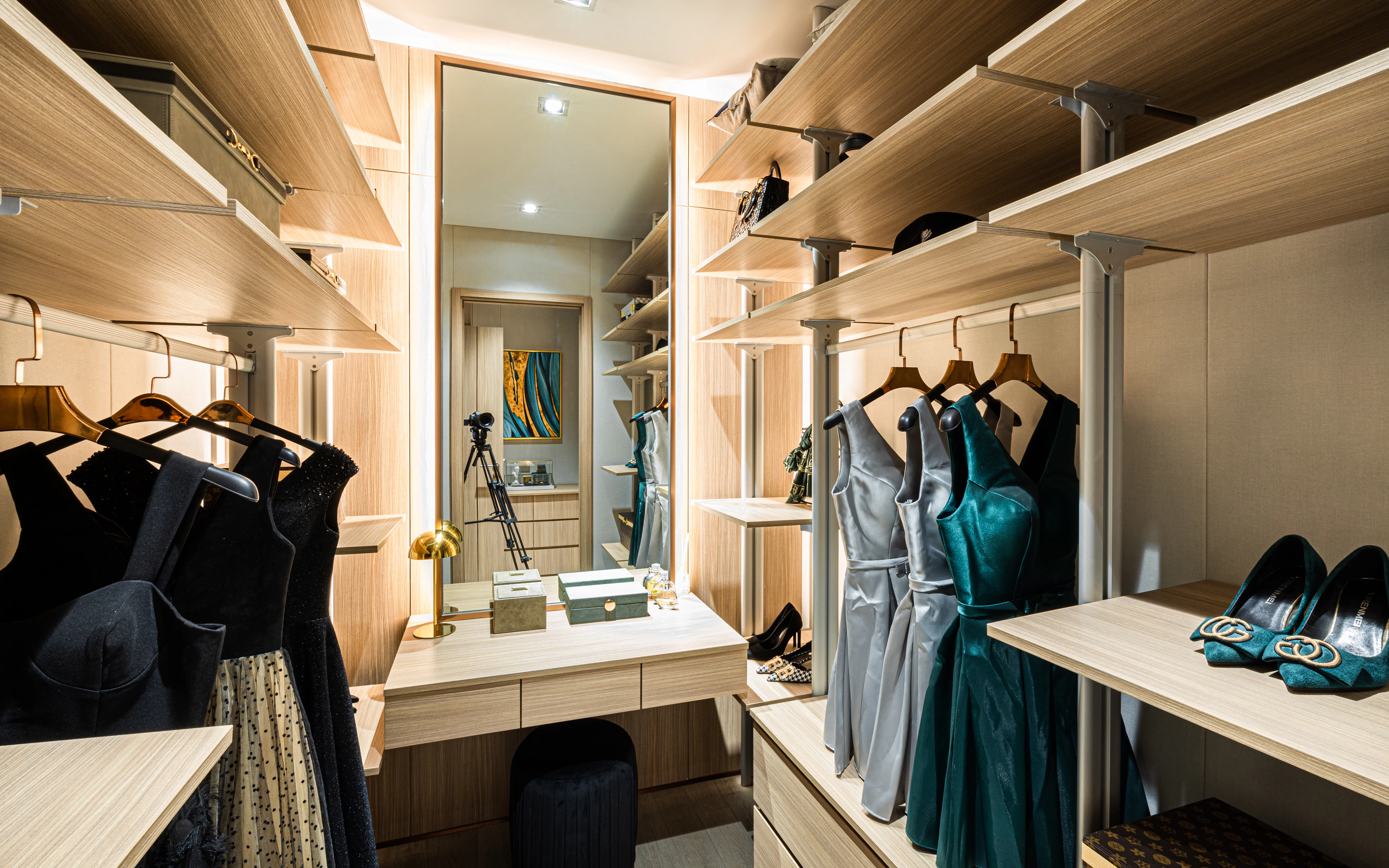 Warm lit walk-in closet with open hanging and a dressing table